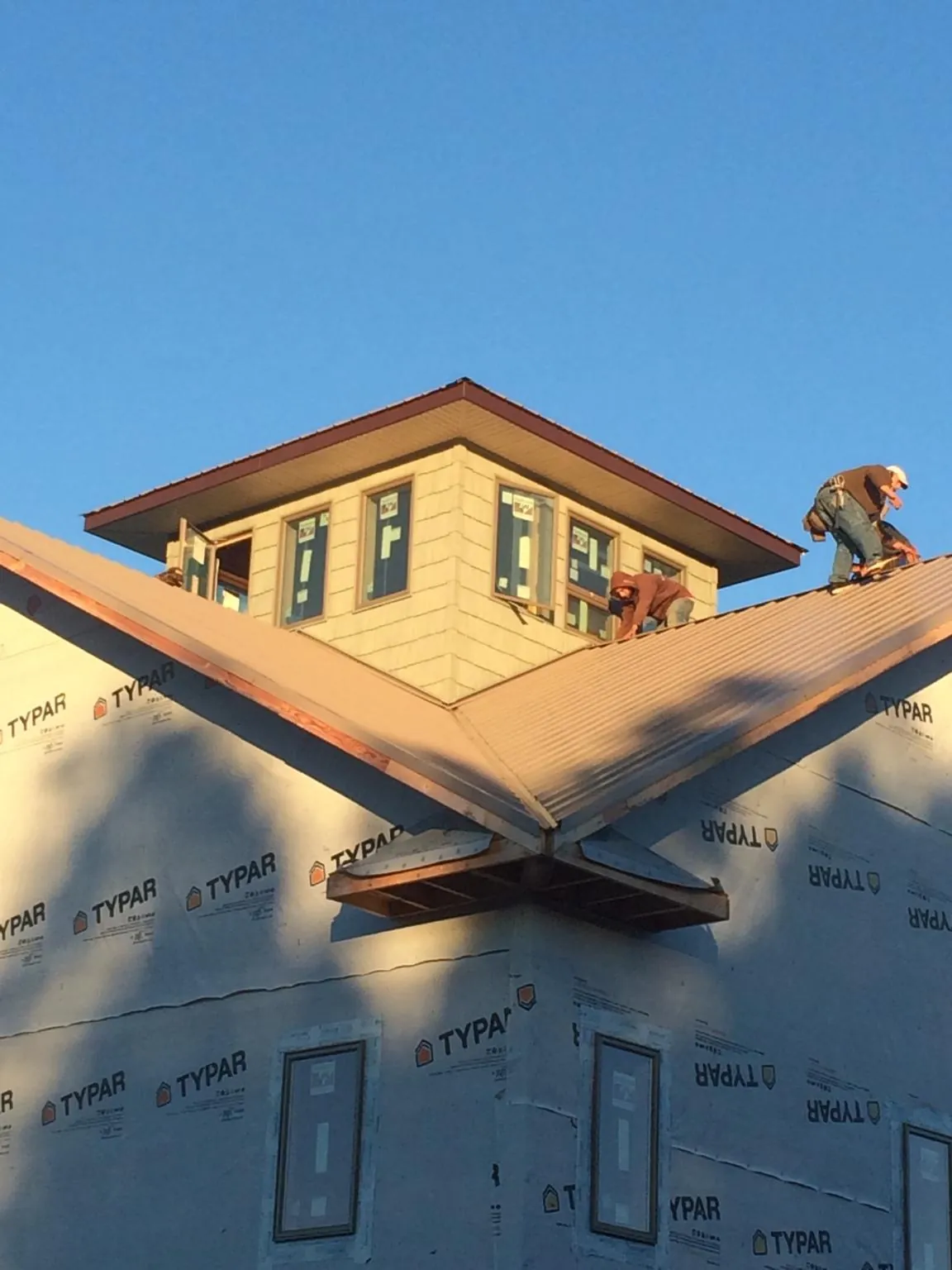 Roofers working around a rooftop cupola on a new metal roof at sunset — Roof Waterproofing in Sharon by Roofing Brothers